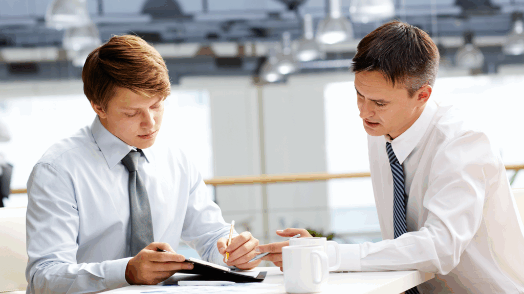 Due uomini in camicia bianca analizzano un documento durante una sessione di Business Coaching.